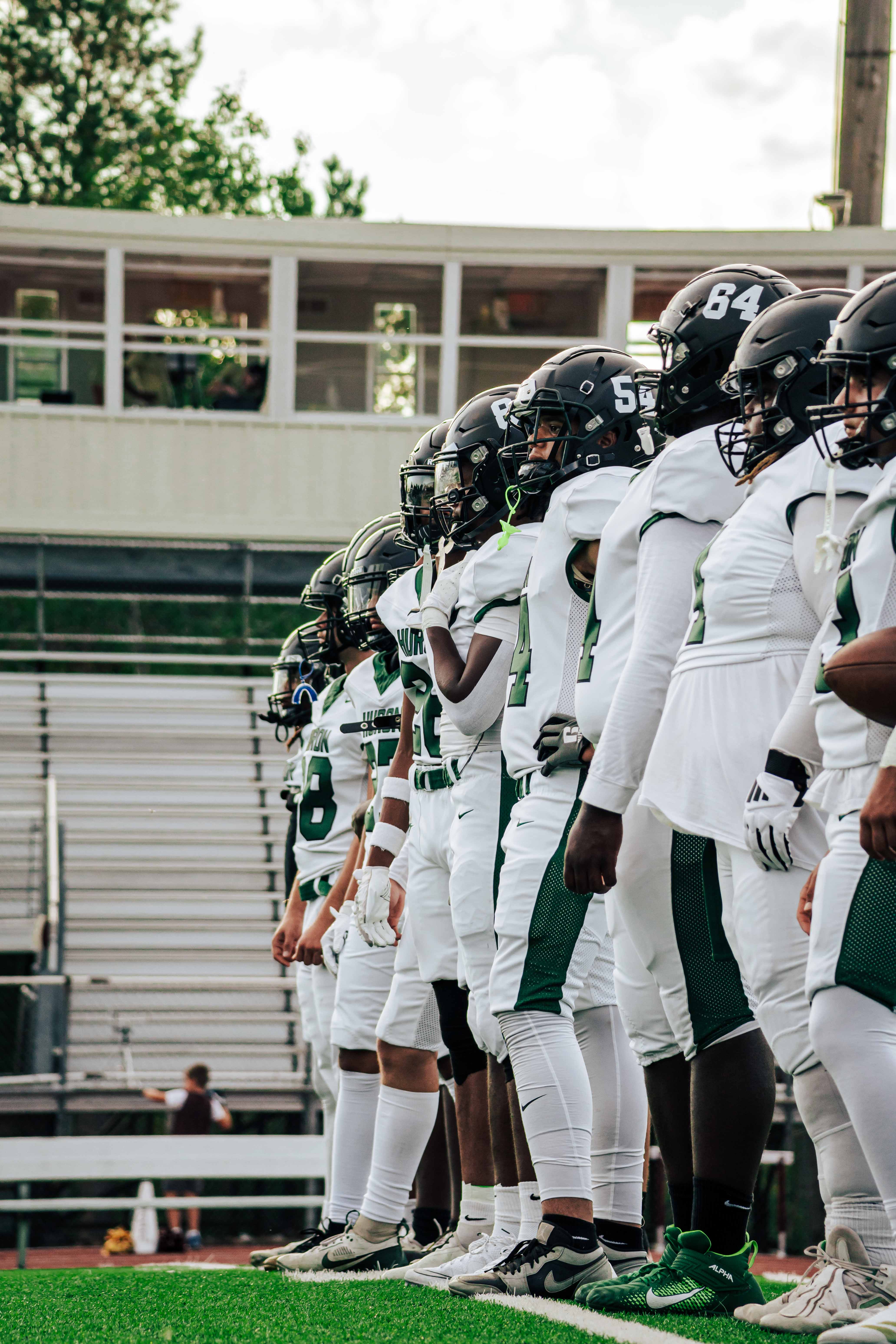 Huron Varsity Football lines up pre game to watch their starters run plays.