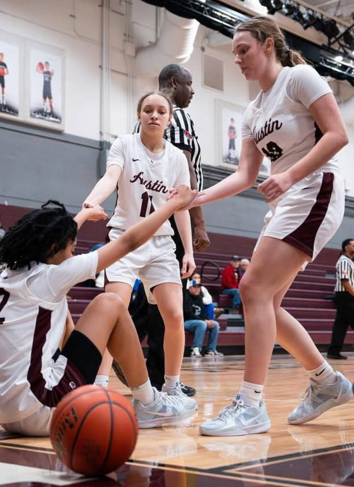 This is a photo of Lady Maroons basketball players helping up a teammate