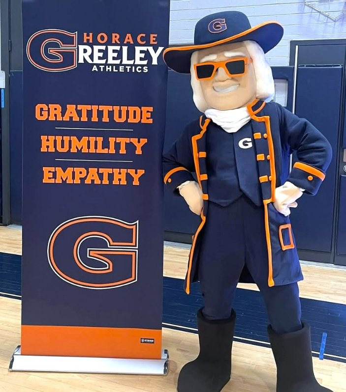 Quaker standing next to banner.