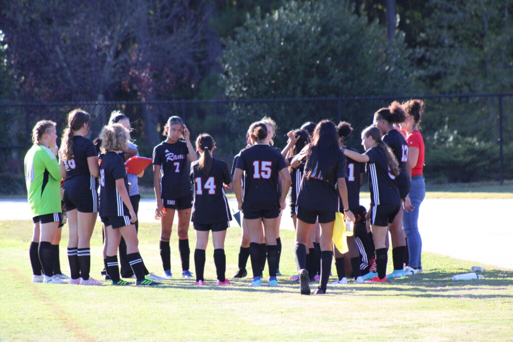 Soccer players standing in a group listening to a coach