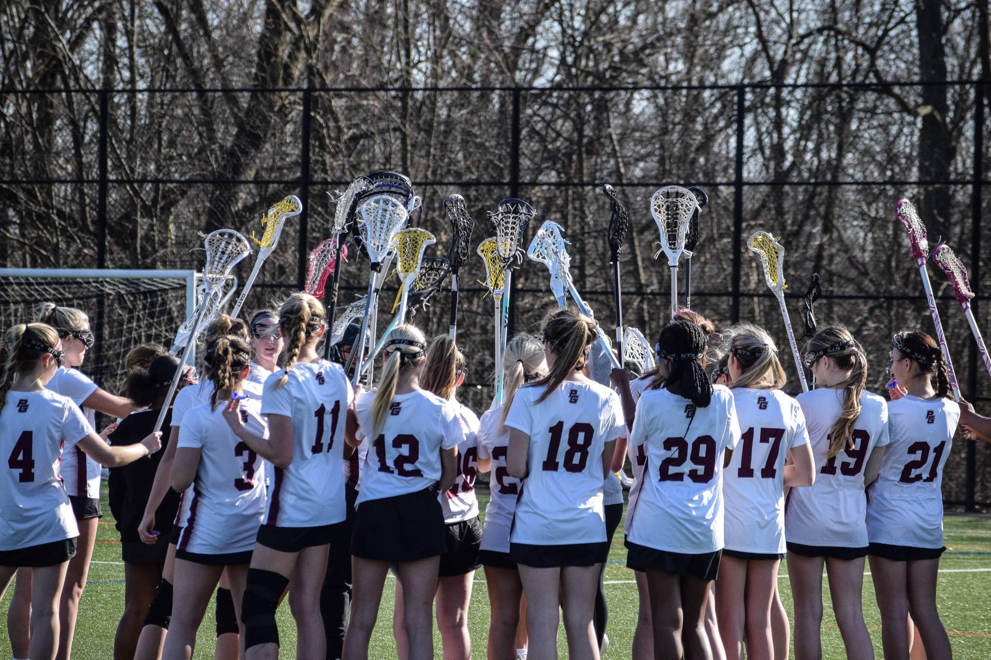 Girls lacrosse team holding up sticks