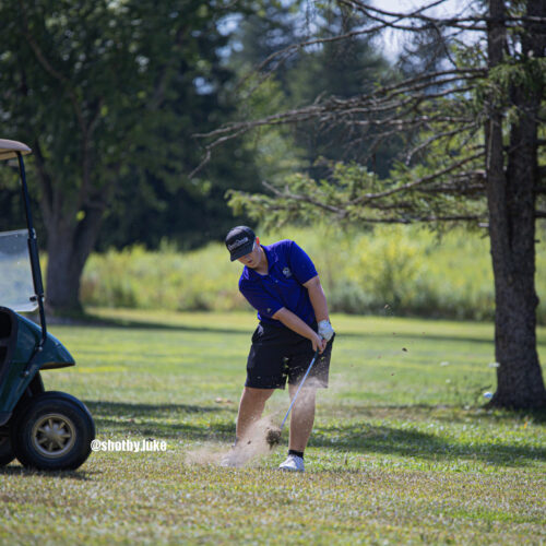 Golfer hits a golf ball and also hits up some dirt from a grassy area