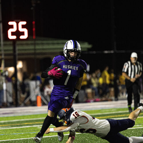 Mifflin County Huskies football player goes around another football player trying to tackle them
