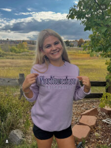 All American Swimmer Annabeth Town Announces Commitment to Northwestern University to swim. Picture of Annabeth wearing a Northwestern sweatshirt.