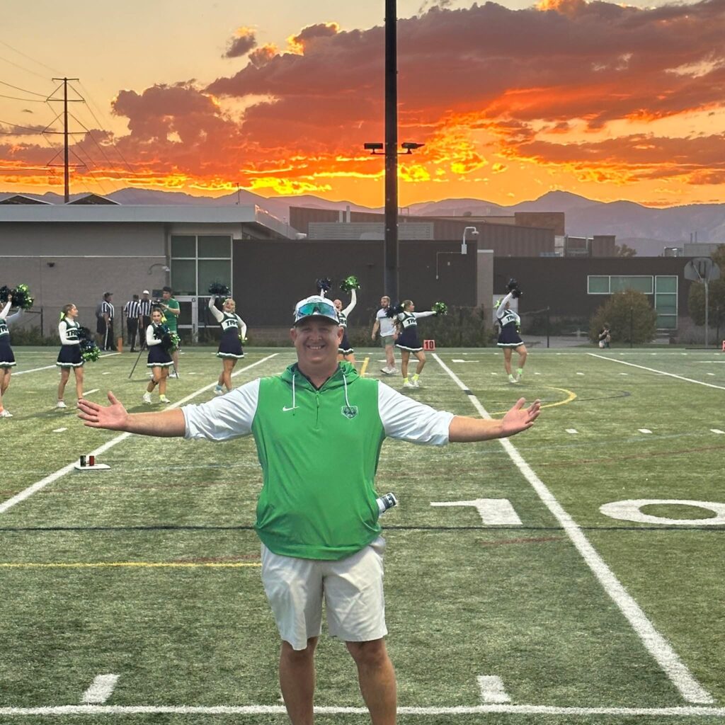 ThunderRidge Athletic Director Josh Stephenson posing with the sunset over the mountains in the background.