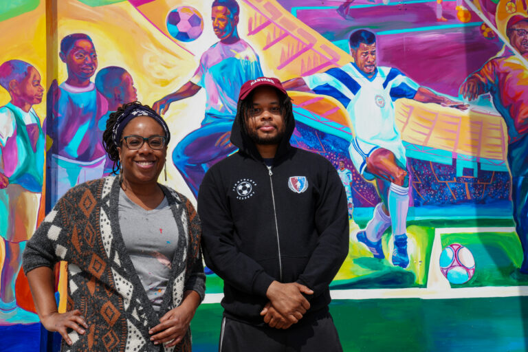 Tia Richardson (artist) and Christopher Perceptions (Jimmy Banks' nephew) stand in front of the new Jimmy Banks mural.