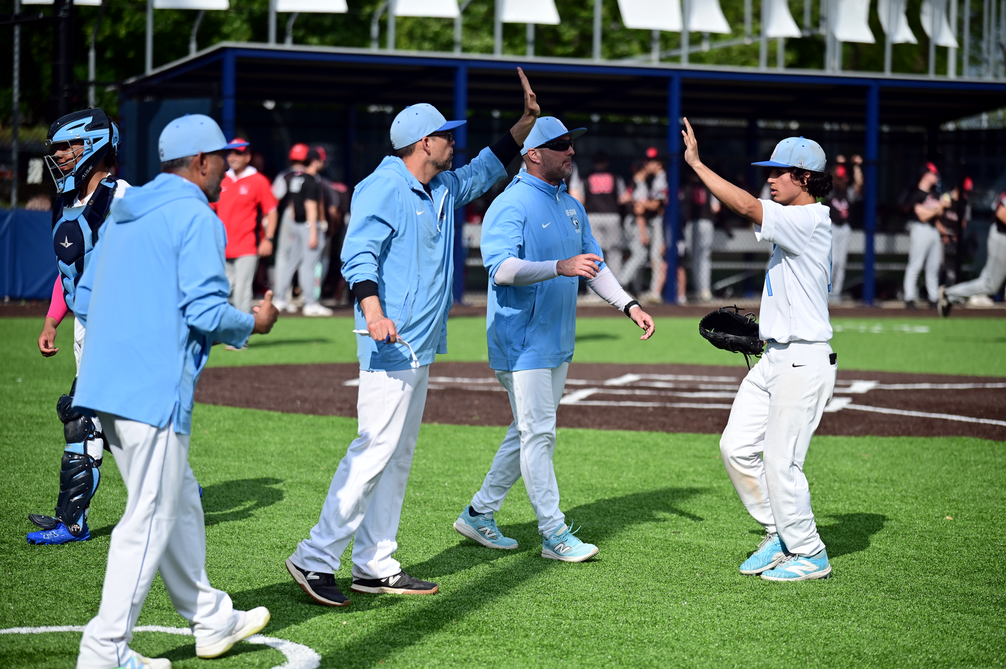 Reagan baseball coaches high-five their student-athlete during a game.