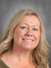 Headshot of a smiling woman with long blonde hair against a grey background.