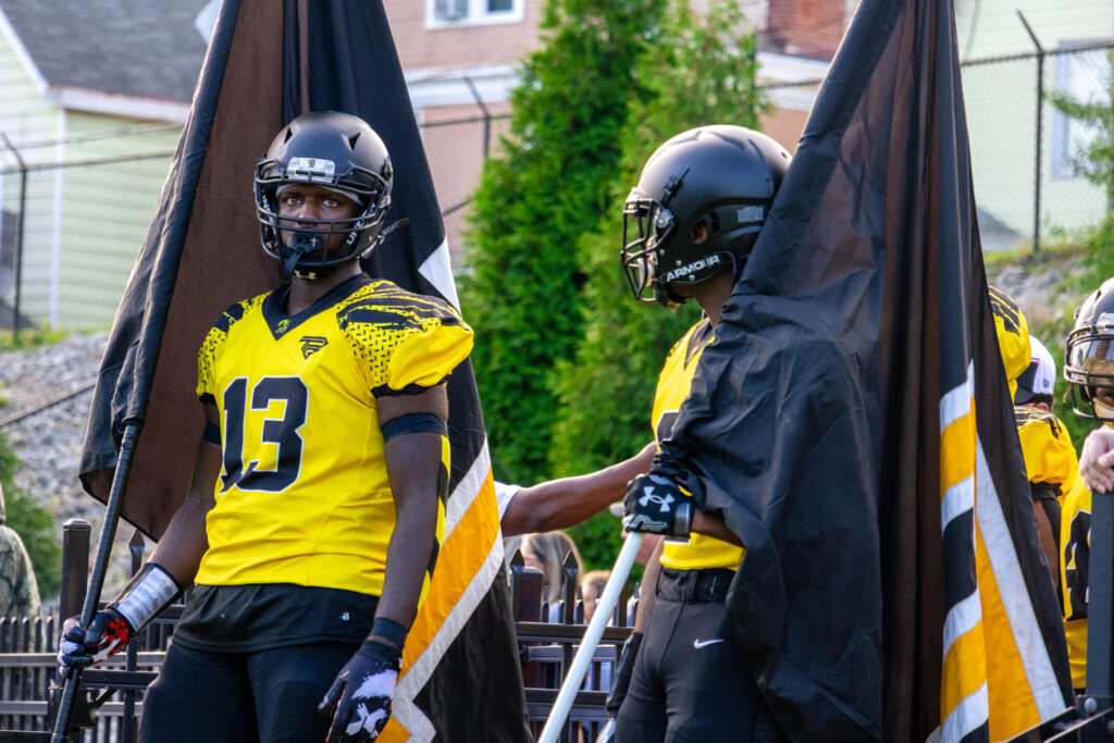 A Titans football player holds a flag and waits for a game to begin.