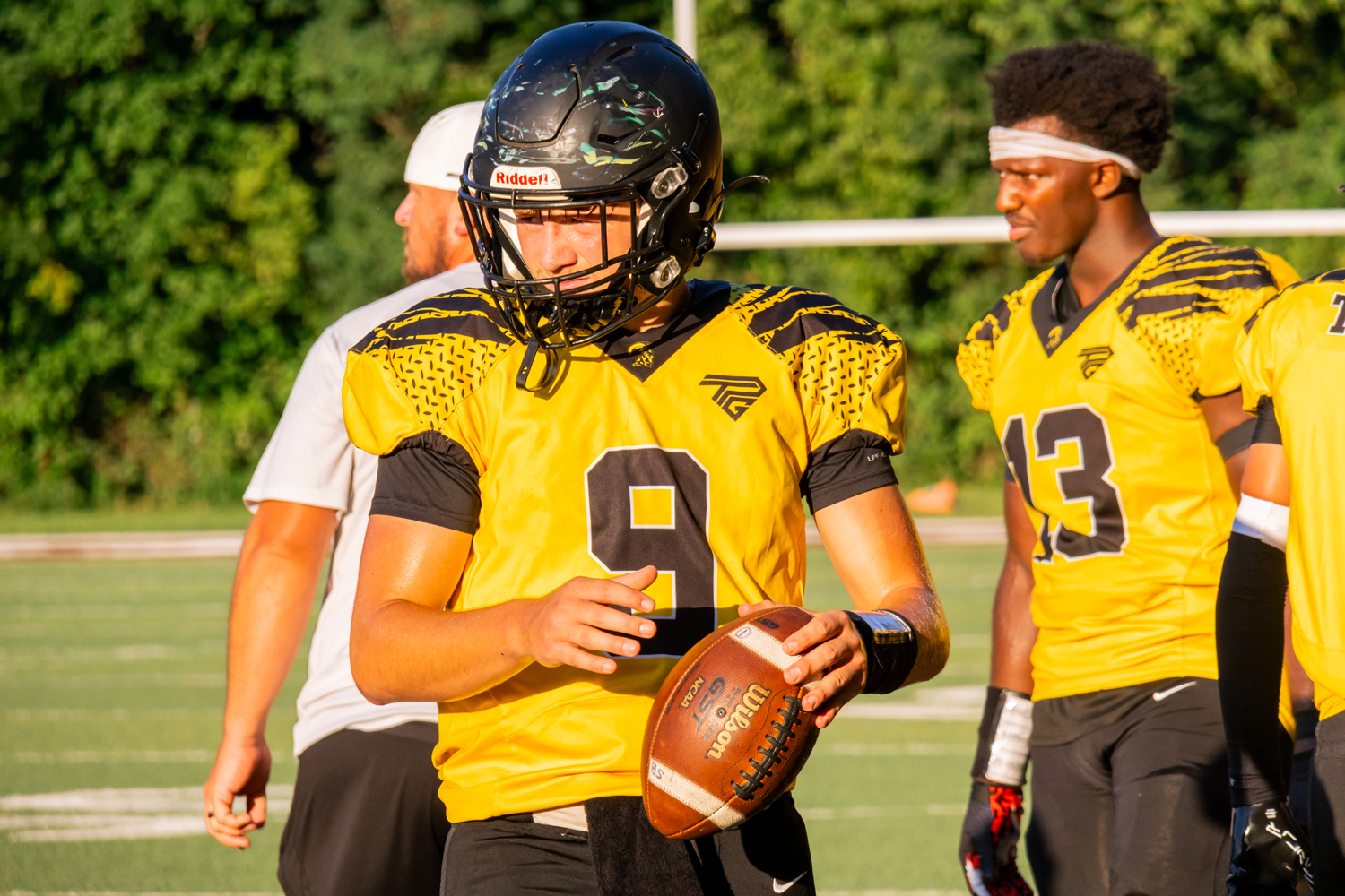An SBEP Titans player holds a football in one hand while looking off to the side.