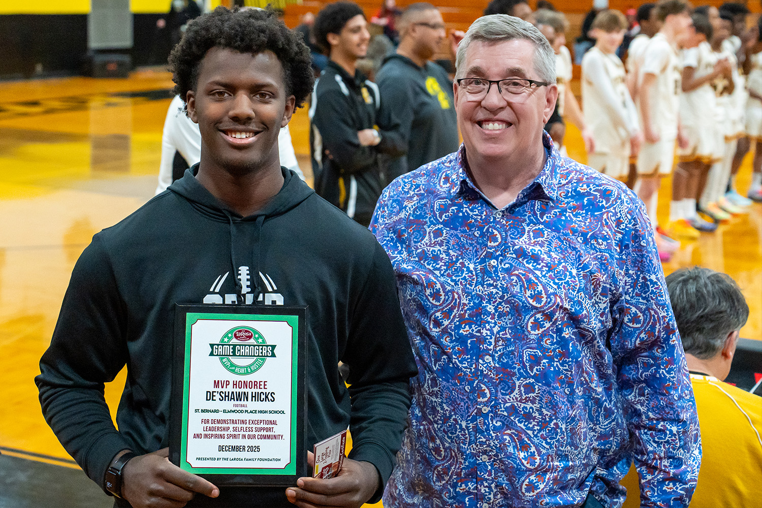 SBEP student De'Shawn Hicks poses with a representative from the LaRosa Family Foundation while holding a plaque for the Game Changers MVP award.