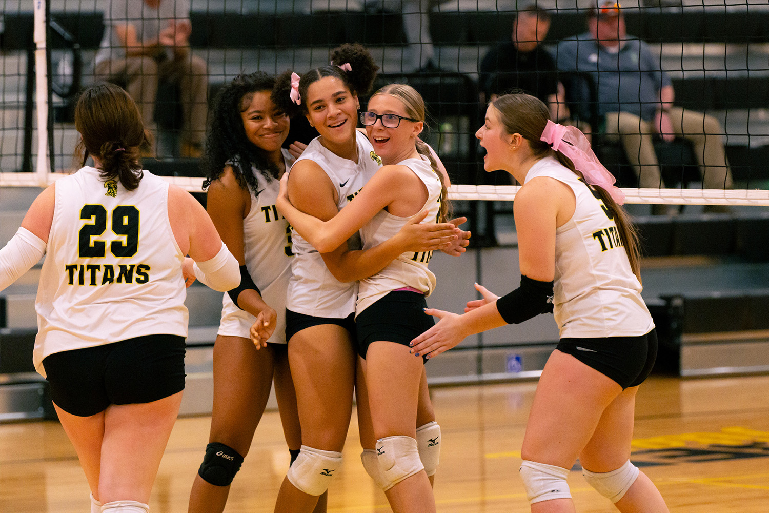 A group of volleyball players celebrate an exciting play.