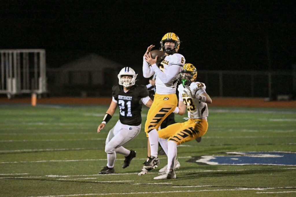 3 football players trying to catch a football