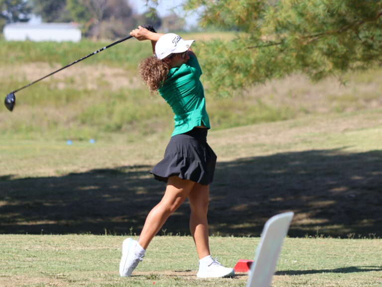 Girl in green uniform swinging golf club