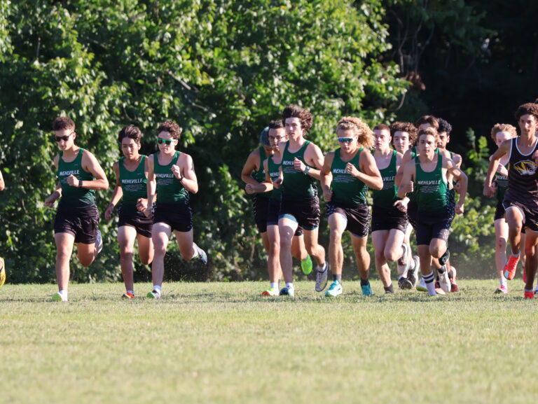 Group of boys running in a field with green uniforms