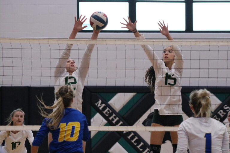 2 volleyball players blocking a ball