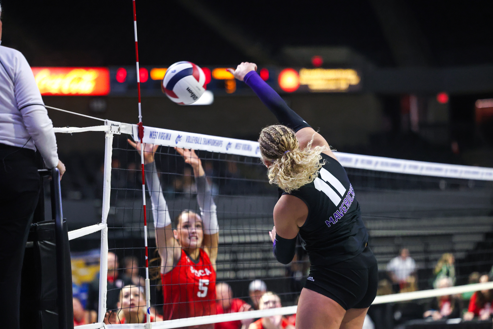 A volleyball player hits one over the net while someone tries to block.