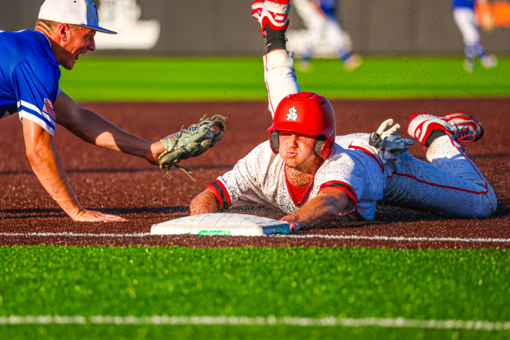 Baseball player sliding into third.