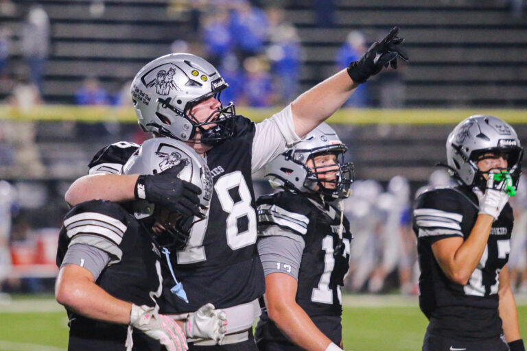 A player puts his arm around a teammate and points to the crowd.