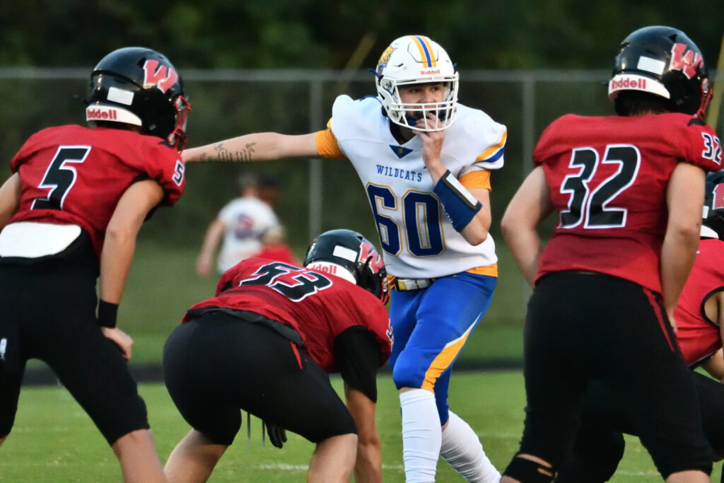 A player in a white jersey yelling to teammates before a ball is going to be snapped.