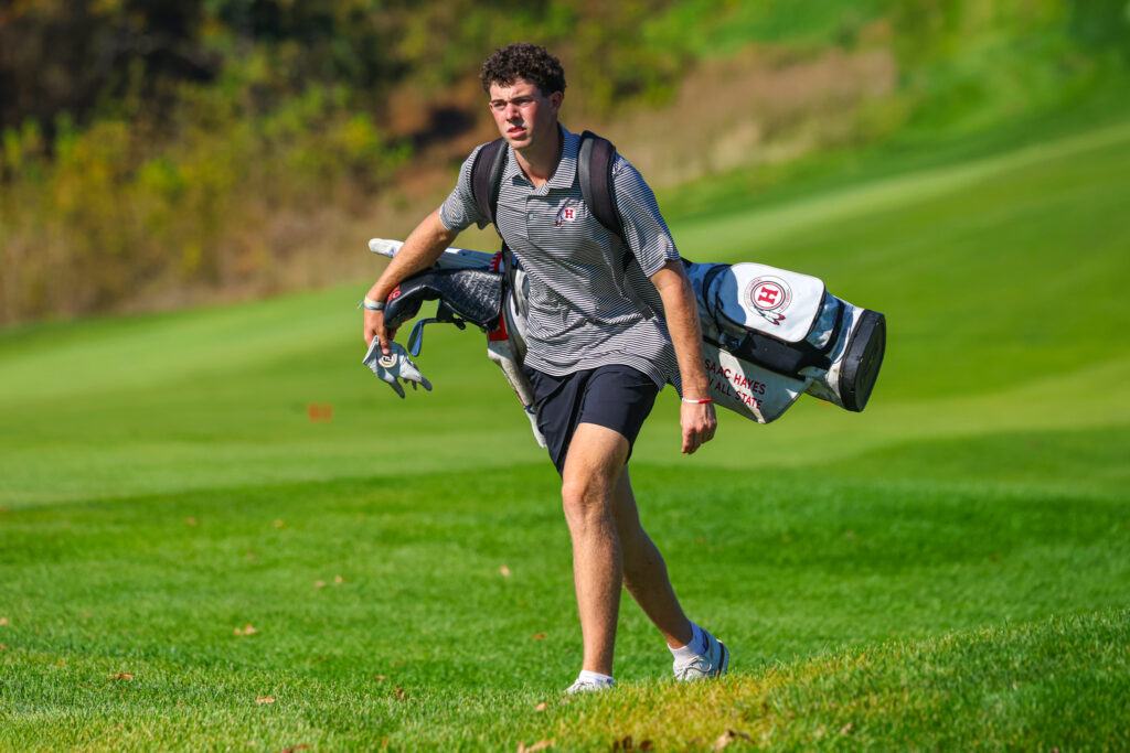A male golfer with a golf bag over his shoulder.