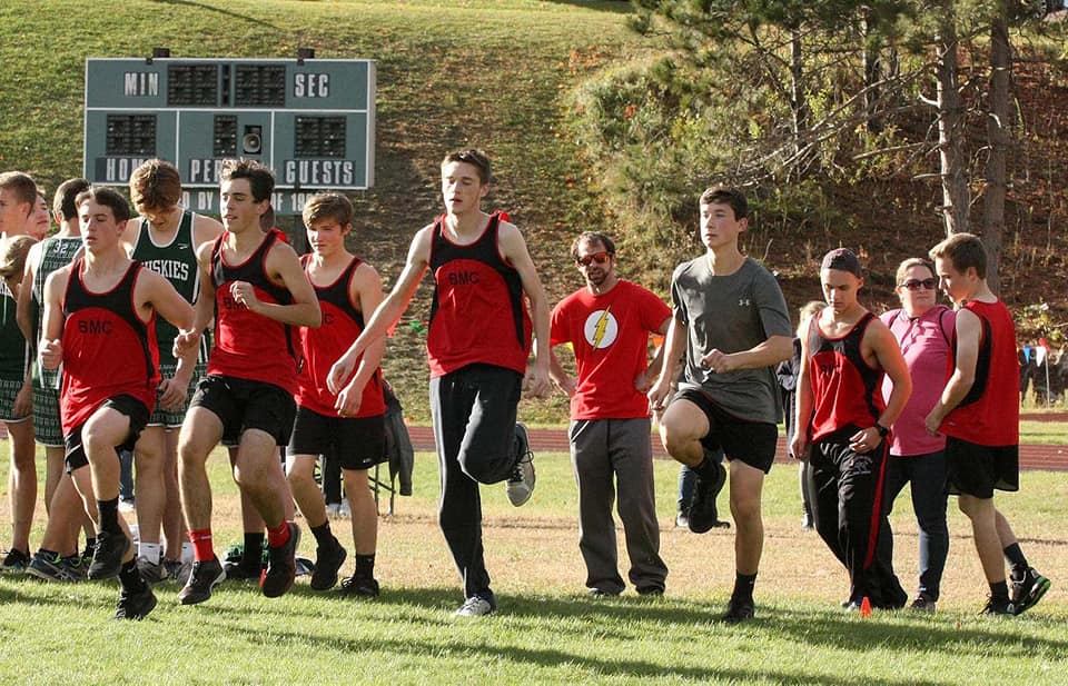 Photo of cross-country coaches watching their student-athletes warming up.