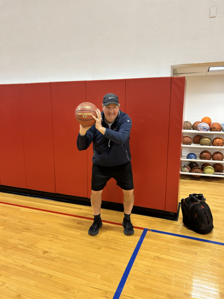 Adult male inside a gymnasium holding a basketball