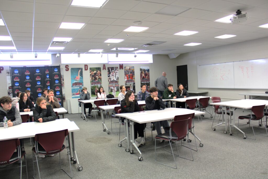 Small group of high school students sitting at desks listening attentively