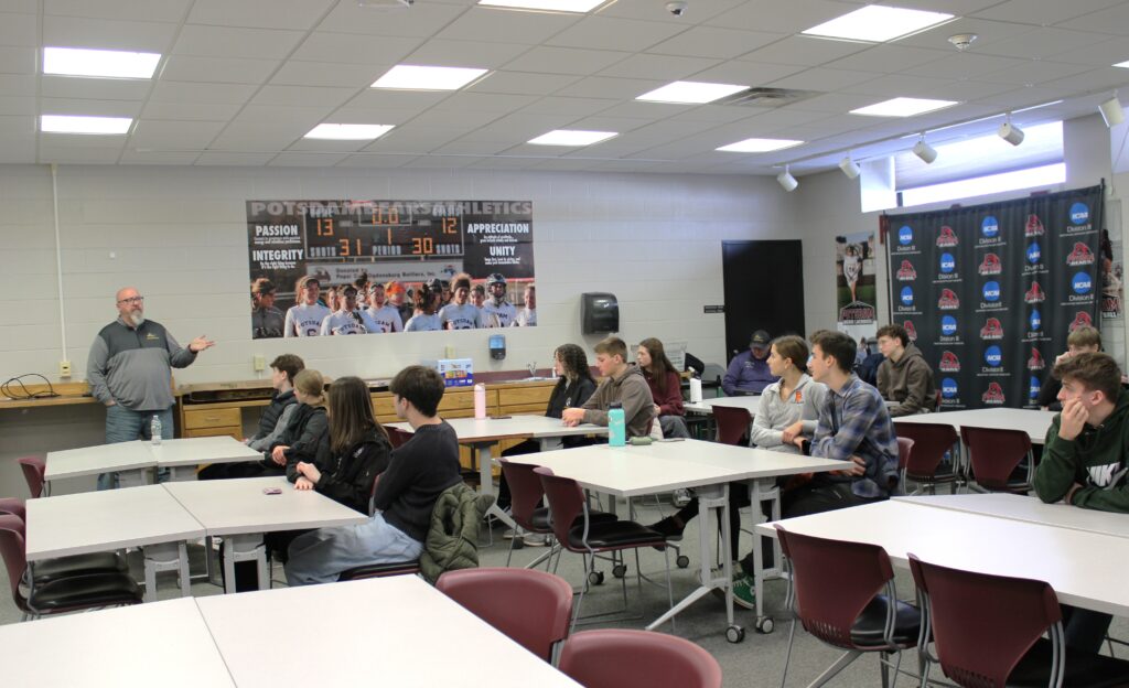 Small group of high school students listening to a male adult speaking
