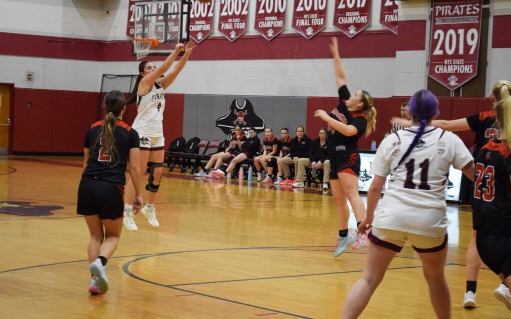 Female high school basketball players wearing white and black and black and red uniforms on the basketball court during a game