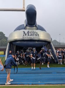 The McDowell football team enters the field before their game by running through a Trojan helmet tunnel.